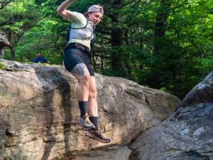 woman jumping off boulder